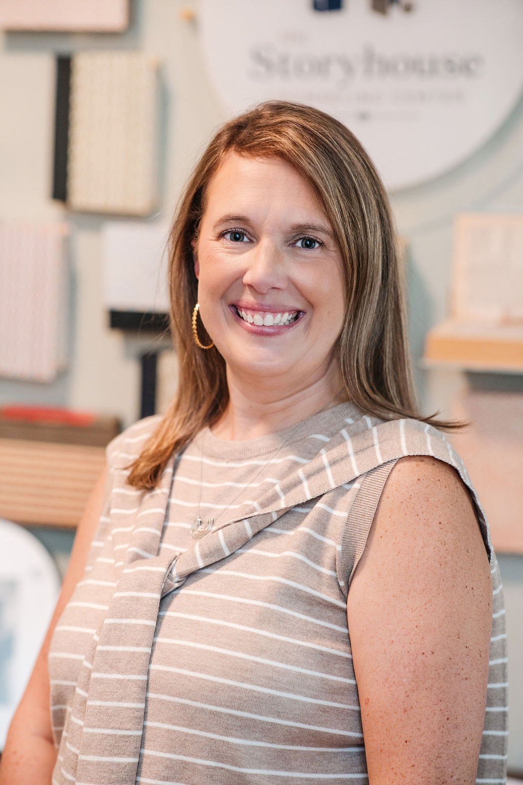 Julie Johnson, LCSW, smiling in front of The Storyhouse Counseling Center logo display