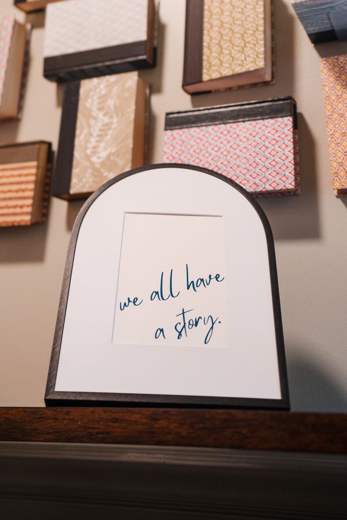 Framed We All Have a Story sign displayed among journals